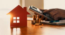 homme avec une calculette avec une maison et des pièces de monnaie