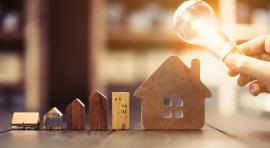 Morceaux de bois en forme d'habitation et ampoule lumineuse pour représenter la gestion de patrimoine immobilier