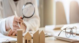 Photo d'une personne tenant une loupe au-dessus de maquettes de maisons