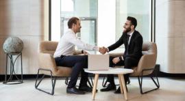 2 hommes se serrant la main devant un ordinateur 