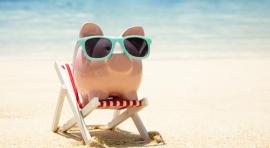 Cochon tirelire posé sur un transat avec des lunettes de soleil sur une plage