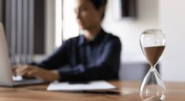 Femme devant son ordinateur avec un sablier au premier plan