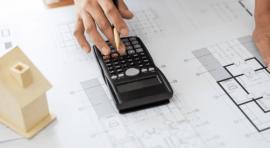 Photo d'une personne avec calculatrice et plan de maison