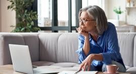 Femme sur son canapé devant son ordinateur pour gérer son assurance vie