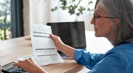 Femme lisant un contrat d'assurance ou de PER et utilisant une calculatrice 