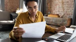 Femme devant un ordinateur en train de lire un document d'investissement