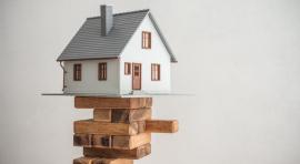 Maquette de maison posée sur des morceaux de bois illustrant le portage immobilier