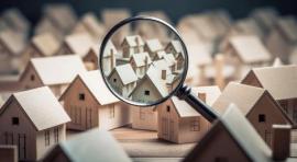 Photo d'une loupe qui zoome sur des maquettes de maisons illustrant differents types de biens immobilier