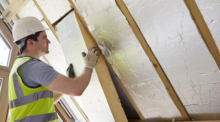 Un ouvrier isole une toiture pour l'amélioration énergétique d'une habitation principale