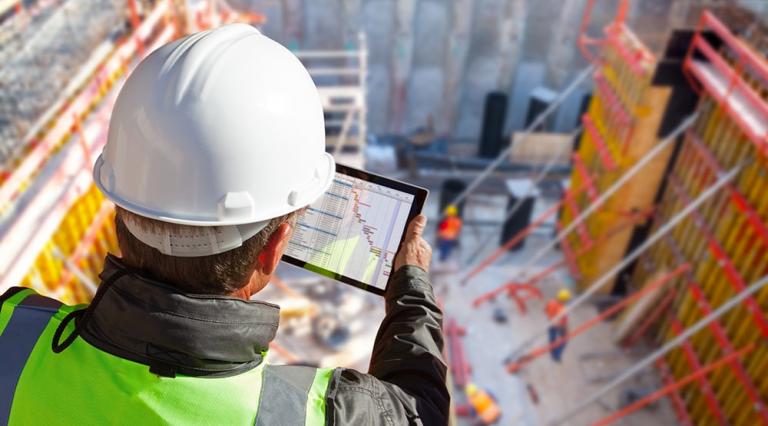 Un homme sur un chantier de construction immobilier consulte sa tablette