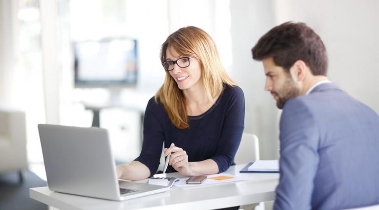 Une banquière et son client étudient avec un ordinateur portable la renégociation d'un crédit immobilier