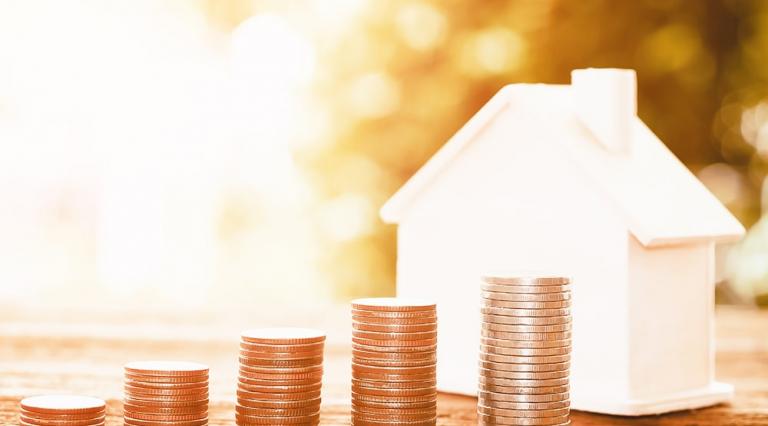 Piles de pièces et petite maison pour illustrer la taxe d'habitation 2020