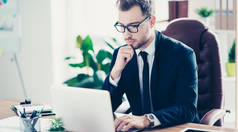 Homme en costume devant un ordinateur