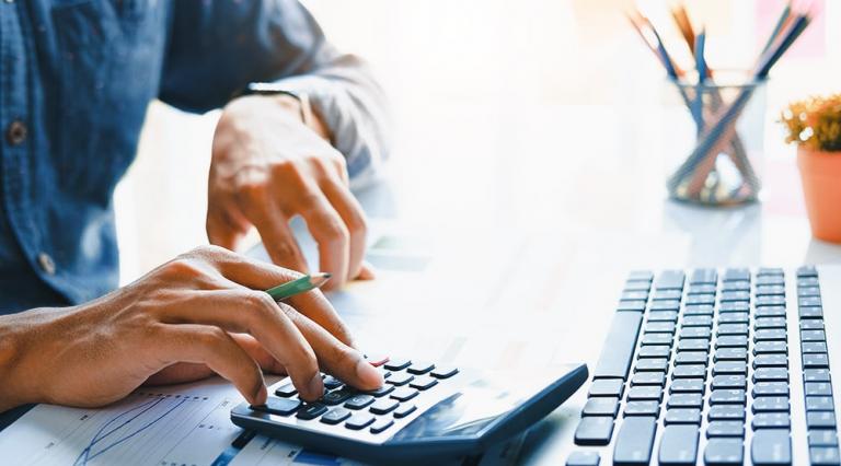 mains d'homme devant un clavier d'ordinateur effectuant des calculs