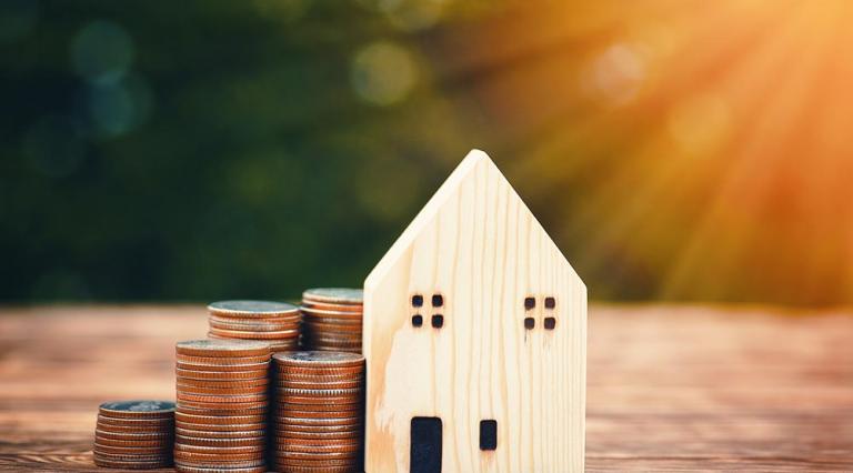 Piles de pièces et petite maison pour illustrer les tendances de prix en immobilier pour l’année 2021