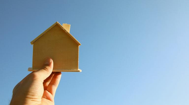 Photo d'une main qui tient une maquette de maison en bois