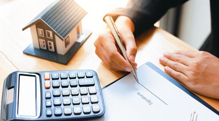 Photo d'une personne avec calculatrice et stylo en main en train de signer un contrat