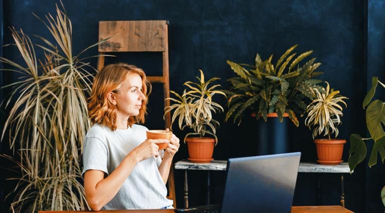 Photo d'une femme devant un écran d'ordinateur avec un mug à la main
