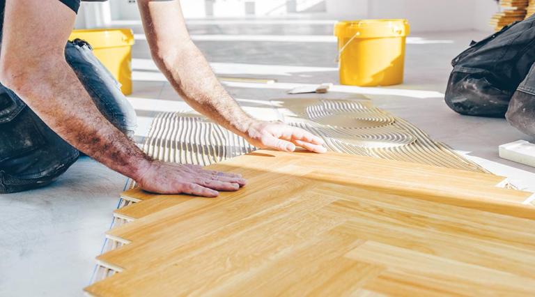 Photo d'un homme en train de poser du parquet