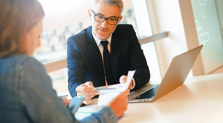 Photo d'un homme et une femme devant un ordinateur pour discuter investissement en SCPI