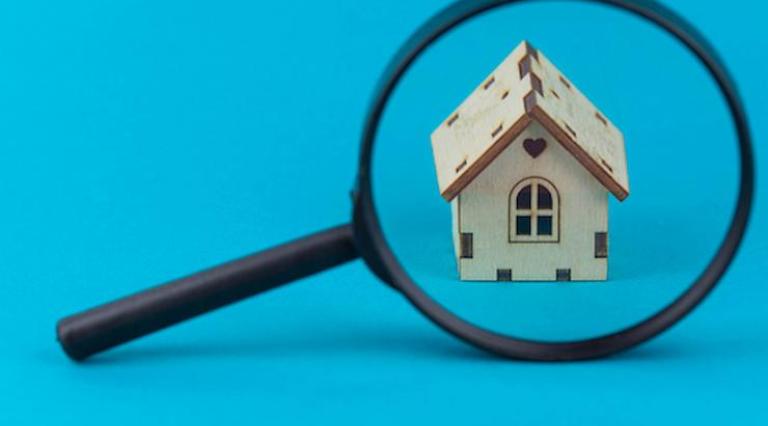 Loupe qui est posée devant une maquette de maison