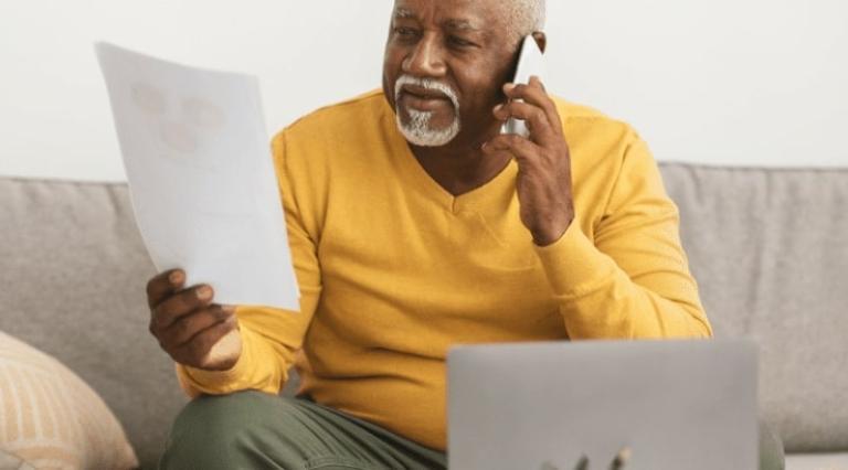 Personne au téléphone lisant un papier devant lui