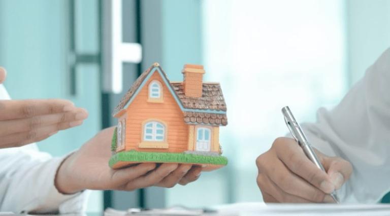 Photo de mains tenant une maquette de maison en bois