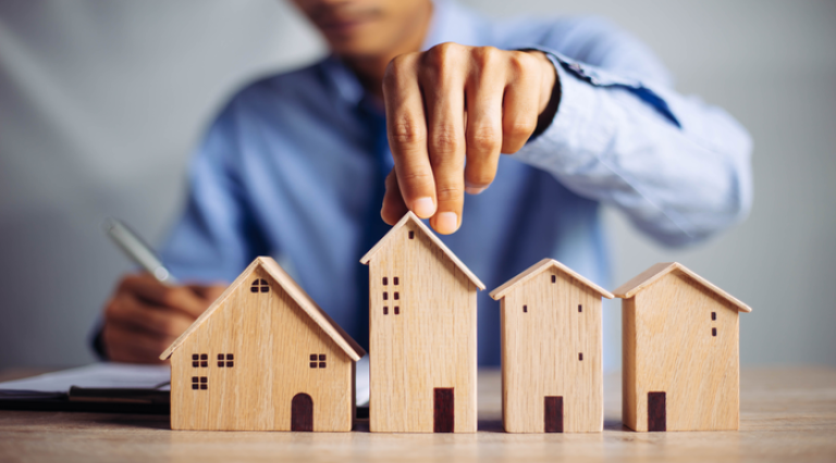 Mains qui touchent des maquettes de maisons en bois symbolisant Pinel Plus