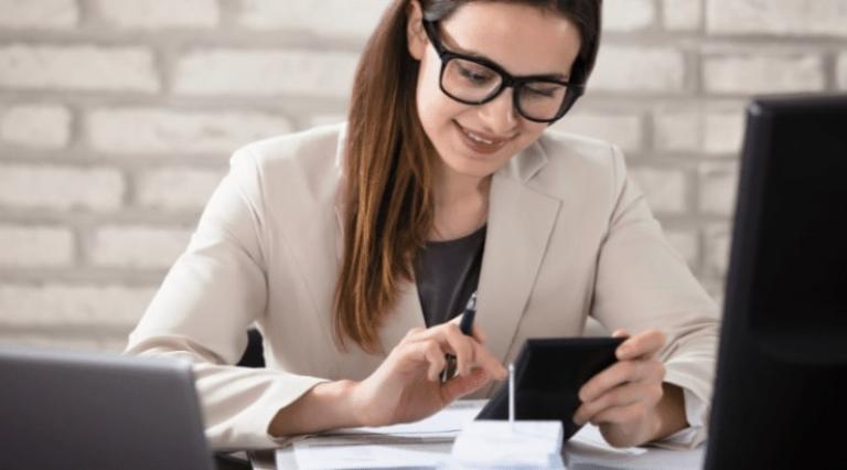 Femme avec sa calculette devant un ordinateur