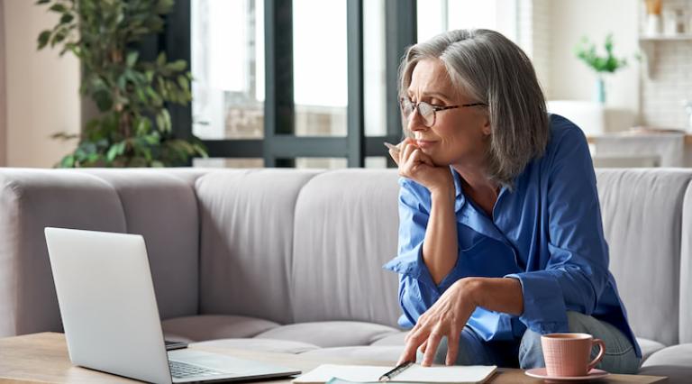 Femme sur son canapé devant son ordinateur pour gérer son assurance vie