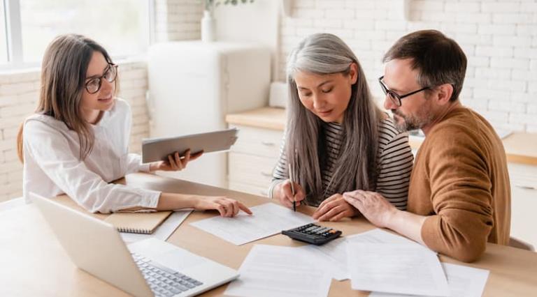 Couple homme/femme avec une conseillère devant des documents d'assurance vie