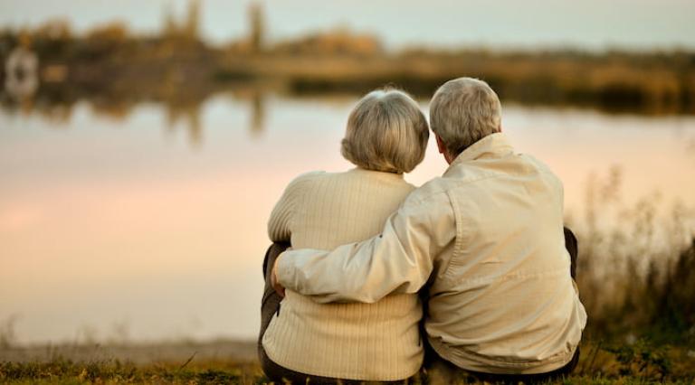 Photo d'un couple de seniors assis au bord de l'eau ayant préparé leur assurance vie