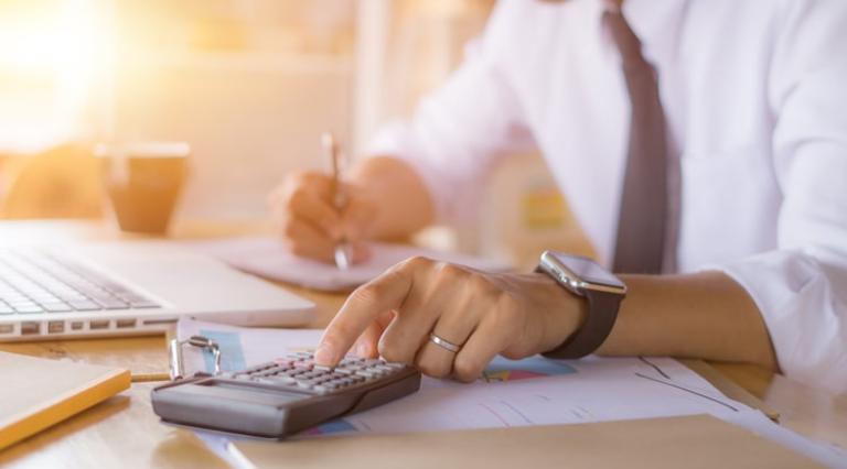 Mains posées sur une calculatrice et un clavier d'ordinateur pour analyser un contrat de nue propriete