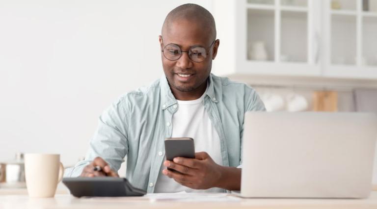 Homme avec un téléphone à la main et une calculatrice à côté analysant son LEP