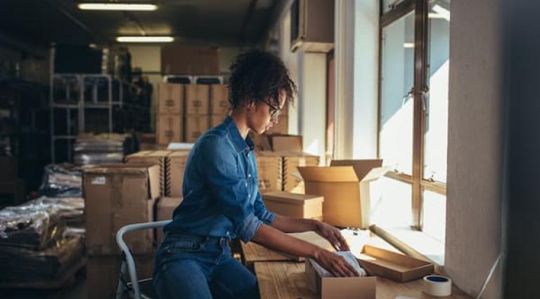 Femme en train d'emballer des choses dans un carton 