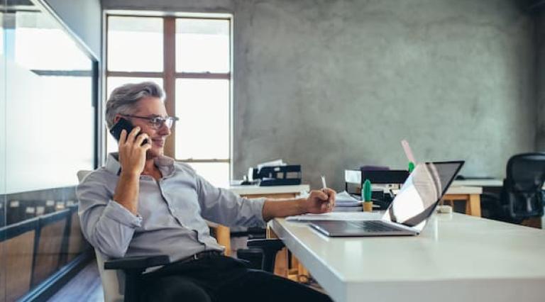 homme au telephone devant un ordinateur pour gerer une gestion sous mandat