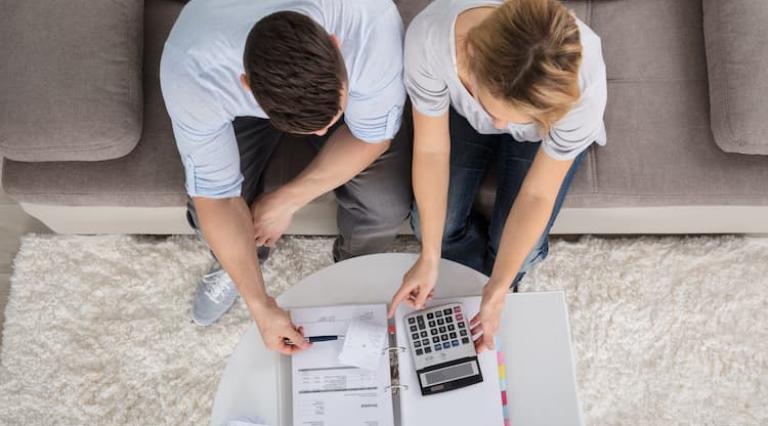 Couple homme/femme devant un dossier d epargne et une calculatrice