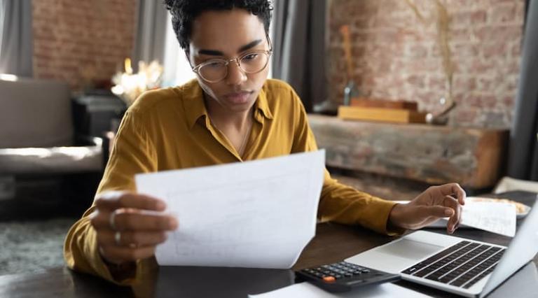 Femme devant un ordinateur en train de lire un document d'investissement