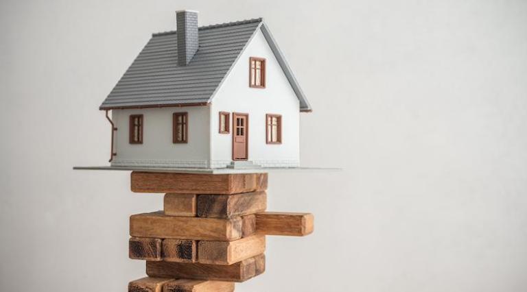 Maquette de maison posée sur des morceaux de bois illustrant le portage immobilier