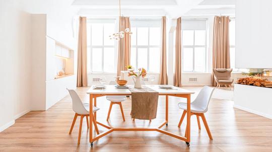 Un magnifique appartement blanc à la décoration épurée avec une table en bois et des chaises scandinaves autour.