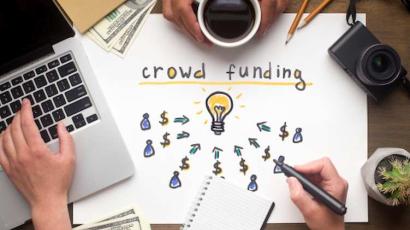 Photo d'un ordinateur posé à côté d'une inscription sur le crowdfunding
