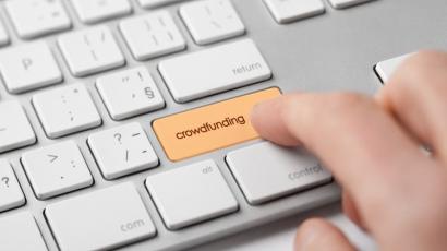 Mains en train d'appuyer sur une touche crowdfunding sur un clavier d'ordinateur