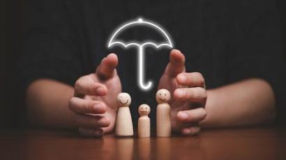 Mains qui entourent des silhouettes en bois d'un couple avec un enfant, avec un parapluie au-dessus d'eux illustrant l'assurance vie