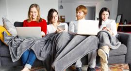 4 personnes sur un canapé consultant Internet pour illustrer l'investissement immobilier en colocation