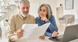 Couple senior homme/femme devant un ordinateur et un contrat de PER