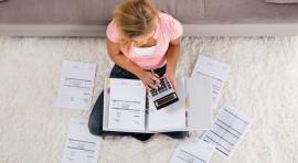 Femme assise en tailleur avec des papiers et une calculatrice analysant ses livrets d'epargne