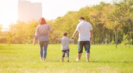Photo d'un couple homme et femme qui tiennent la main d'un enfant dans un parc