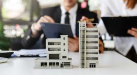 Photo de 2 personnes devant des maquettes d'immeubles pour acheter en vefa