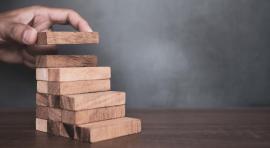 Main qui empile des morceaux de bois symbolisant les meilleurs placements sans risques