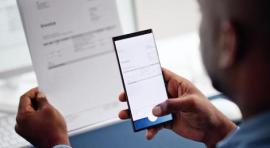 Photo d'un homme en train de faire une photo d'un document avec son smartphone illustrant l impact de la digitalisation sur le locatif